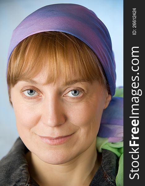 Portrait of adult woman in a bright headscarf. Look at the camera. Blue background. Closeup. Portrait of adult woman in a bright headscarf. Look at the camera. Blue background. Closeup.