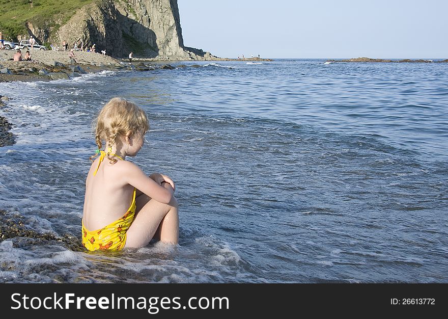 Little girl sitting on the bank of Japan Sea