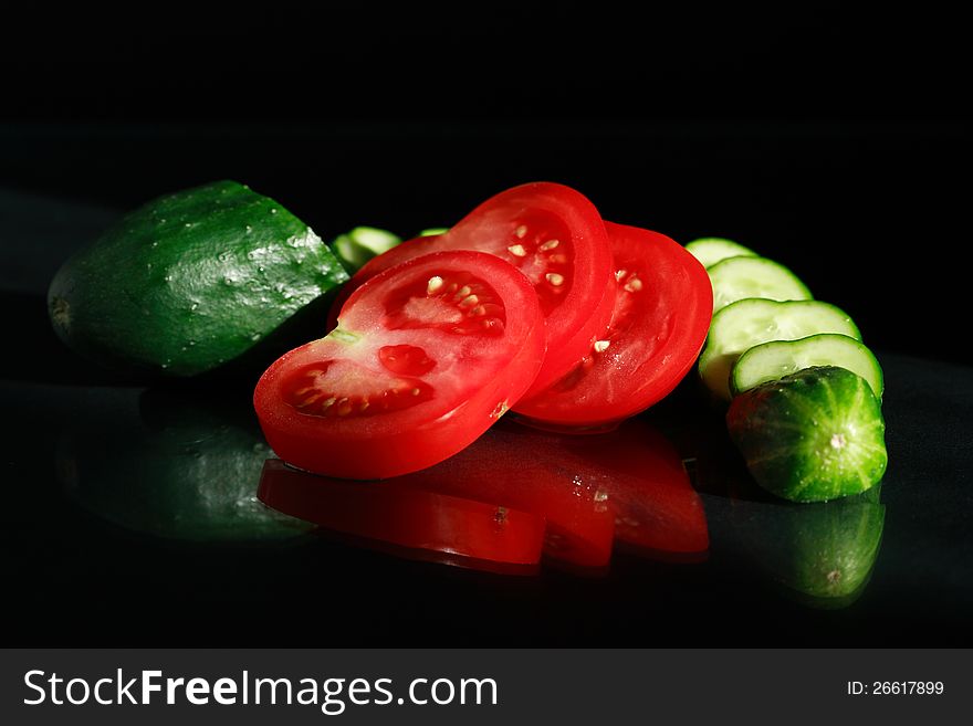 Sliced tomatoes and cucumber on black background. Sliced tomatoes and cucumber on black background