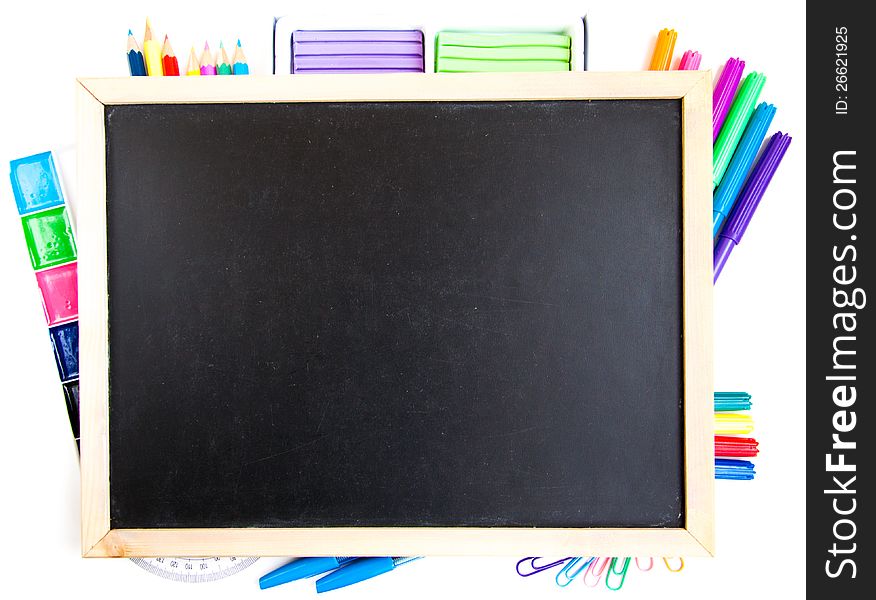 Small elementary blackboard with various paints, crayons and pencils on a white background. Small elementary blackboard with various paints, crayons and pencils on a white background