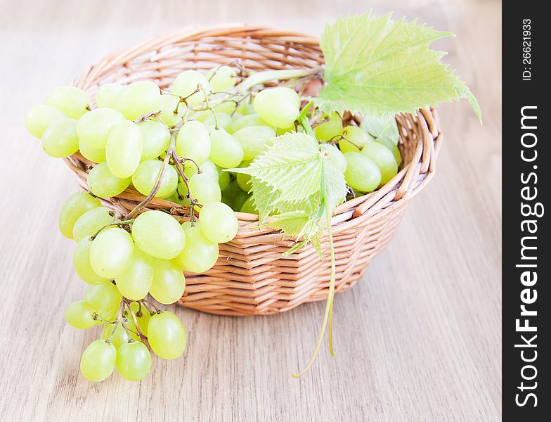 Basket with grape cluster with leaves on a table