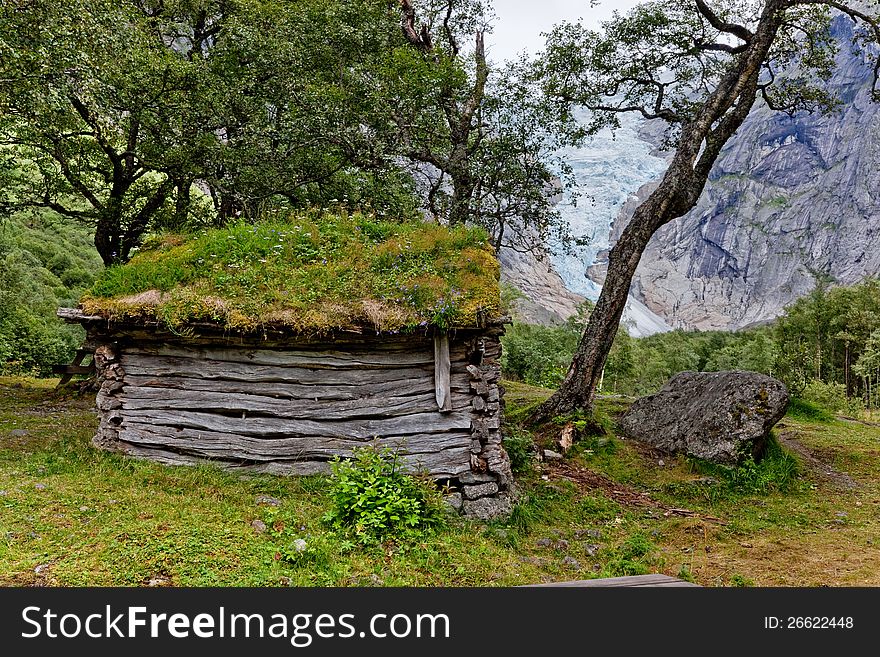 Abandoned hut with a roof covered with grass in Norwegian forest near glacier. Abandoned hut with a roof covered with grass in Norwegian forest near glacier