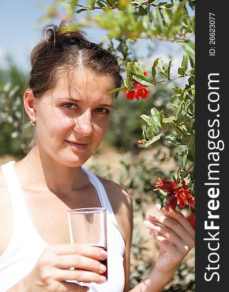 Adult woman drinking pomegranate juice in the garden