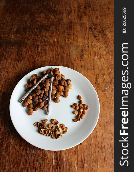 White plate of apricot seeds on a rustic table. White plate of apricot seeds on a rustic table