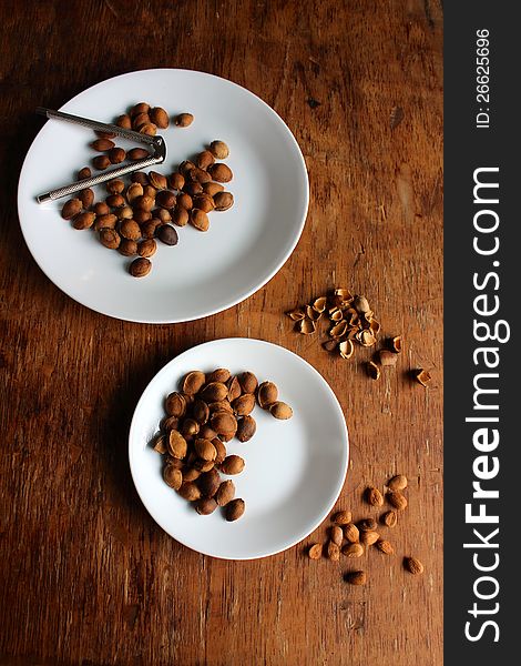 Two plates of apricot seeds on a rough table