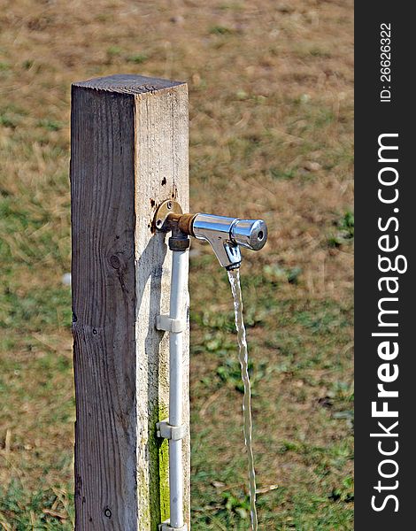 Photo of running water coming from a standpipe attached to a wooden post. Photo of running water coming from a standpipe attached to a wooden post.