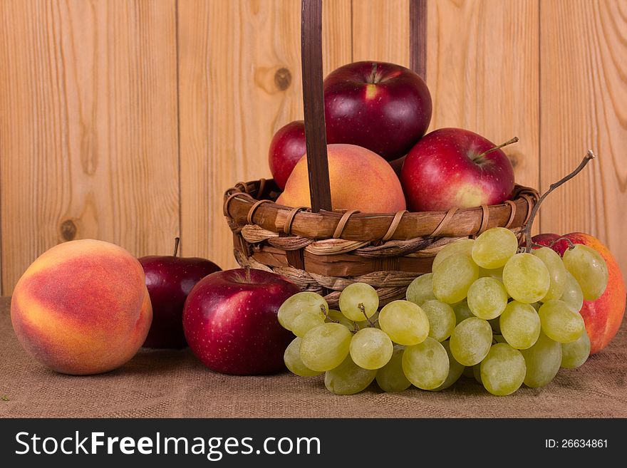 Ripe grapes, peach, apple in the basket. Ripe grapes, peach, apple in the basket