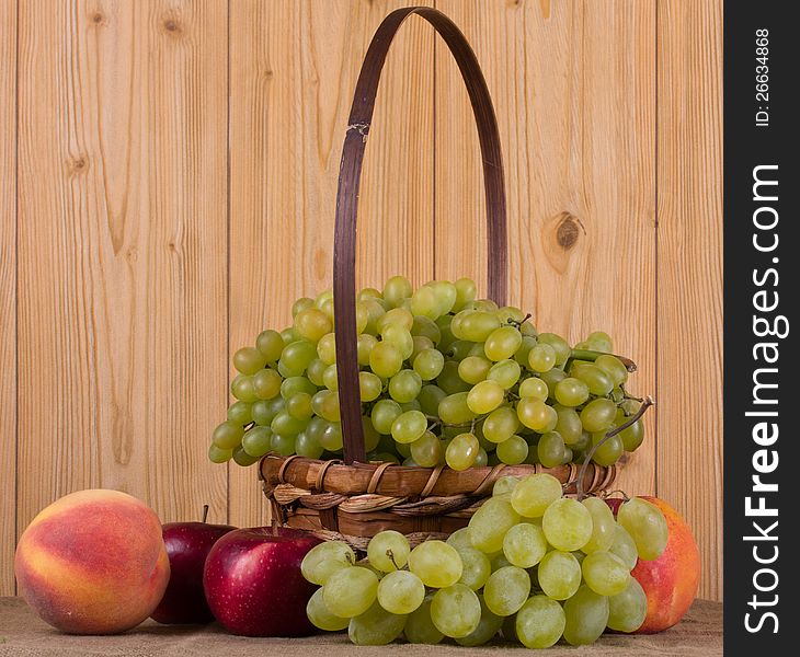 Ripe grapes, peach, apple in the basket. Ripe grapes, peach, apple in the basket