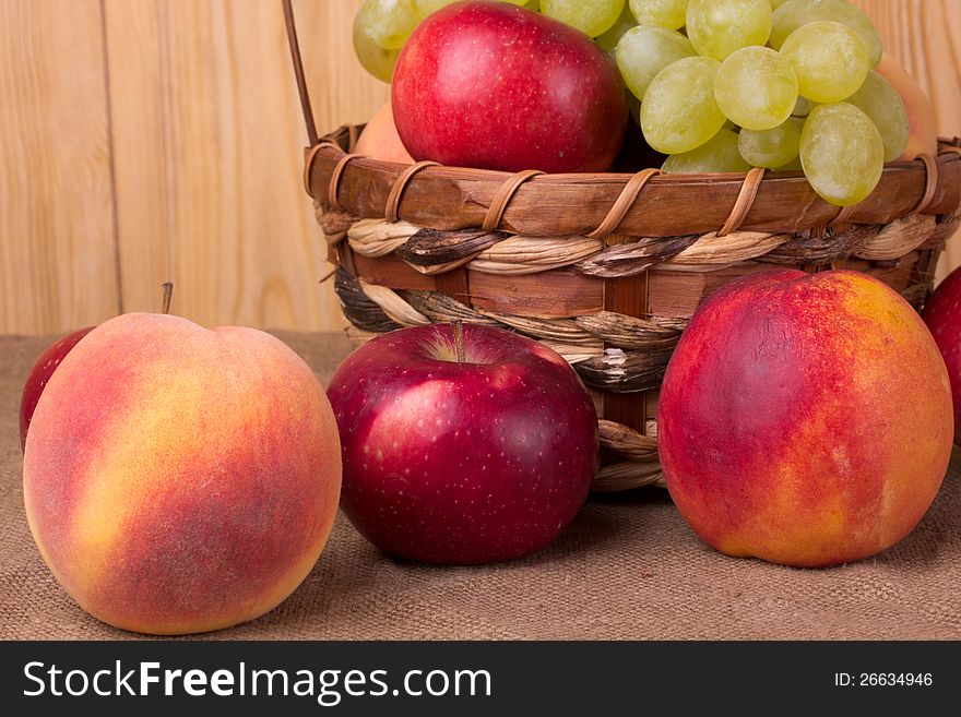 Ripe grapes, peach, apple in the basket. Ripe grapes, peach, apple in the basket