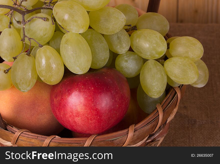 Ripe grapes, peach, apple in the basket. Ripe grapes, peach, apple in the basket
