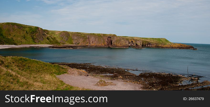 Stonehaven Coastline by Dunnottar Castle,Stonehaven, Grampian, Scotland, U.K Dunnottar Castle, &#x22;fort on the shelving slope&#x22;&#x29; is a ruined medieval fortress located upon a rocky headland on the northeastern coast of Scotland, about 2 miles &#x28;3.2 km&#x29; south of Stonehaven. The surviving buildings are largely of the 15th and 16th centuries, but the site is believed to have been fortified in the Early Middle Ages. Dunnottar has played a prominent role in the history of Scotland through to the 18th-century Jacobite risings because of its strategic location and defensive strength. Dunnottar is best known as the place where the Honours of Scotland, the Scottish crown jewels, were hidden from Oliver Cromwell&#x27;s invading army in the 17th century. The property of the Keiths from the 14th century, and the seat of the Earl Marischal, Dunnottar declined after the last Earl forfeited his titles by taking part in the Jacobite rebellion of 1715. The castle was restored in the 20th century and is now open to the public. The ruins of the castle are spread over 1.4 hectares &#x28;3.5 acres&#x29;, surrounded by steep cliffs that drop to the North Sea, 160 feet &#x28;49 m&#x29; below. A narrow strip of land joins the headland to the mainland, along which a steep path leads up to the gatehouse. The various buildings within the castle include the 14th-century tower house as well as the 16th-century palace. Dunnottar Castle is a scheduled monument, and twelve structures on