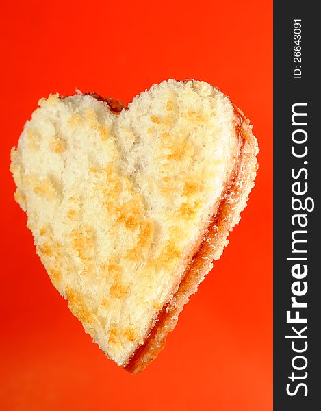 A heart-shaped jam sandwich on a bright red background. A heart-shaped jam sandwich on a bright red background