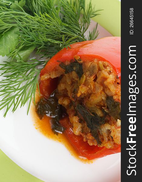 Stuffed Red Bell Pepper Filled with Rice, Meat, Onion and Parsley close up on white plate