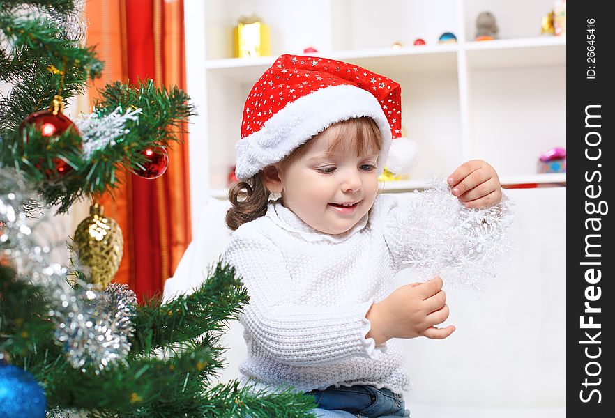 Little girl in Santa's hat looking at the snowflake. Little girl in Santa's hat looking at the snowflake