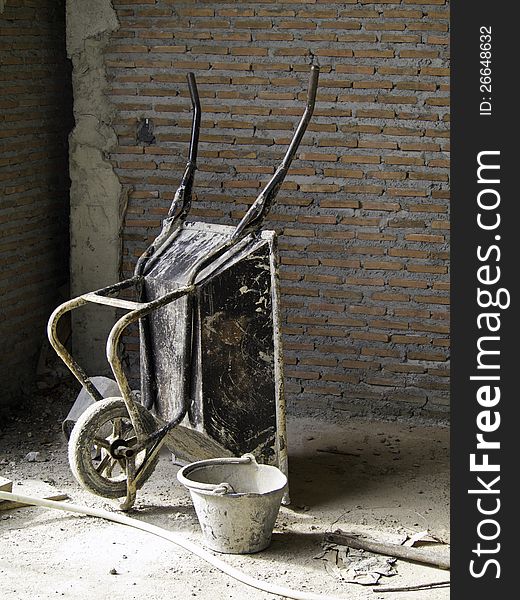 Wheelbarrow on construction site with brick wall background