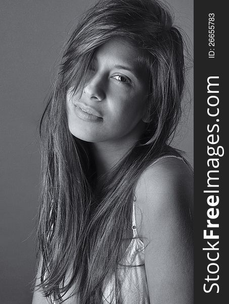 A black and white portrait of a pretty young woman with long, messy hair, smiling slightly at the viewer. A black and white portrait of a pretty young woman with long, messy hair, smiling slightly at the viewer