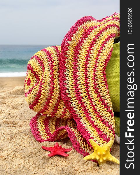 Summer holidays - green beach bag on the seacoast, pink straw hat and funny sea stars. Summer holidays - green beach bag on the seacoast, pink straw hat and funny sea stars