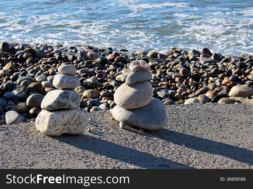 Rocky beach with waves washing over the shore and many pilings of zen stones facing the early morning sunshine. Rocky beach with waves washing over the shore and many pilings of zen stones facing the early morning sunshine.