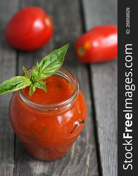 Tomato passata in a jar and two tomatoes