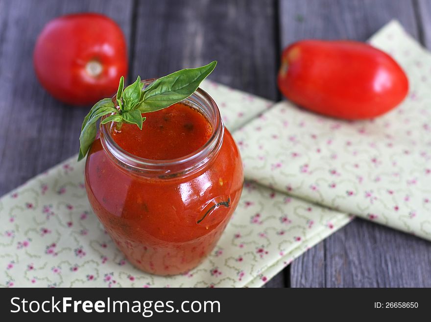 Tomato passata in a jar and two tomatoes