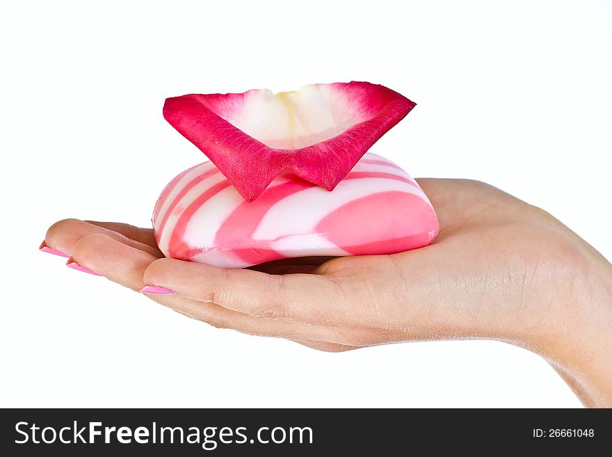 Pink soap bar with rose petals on female hand