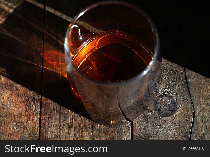 Closeup of glass of seasoned whiskey on old wooden surface. Closeup of glass of seasoned whiskey on old wooden surface