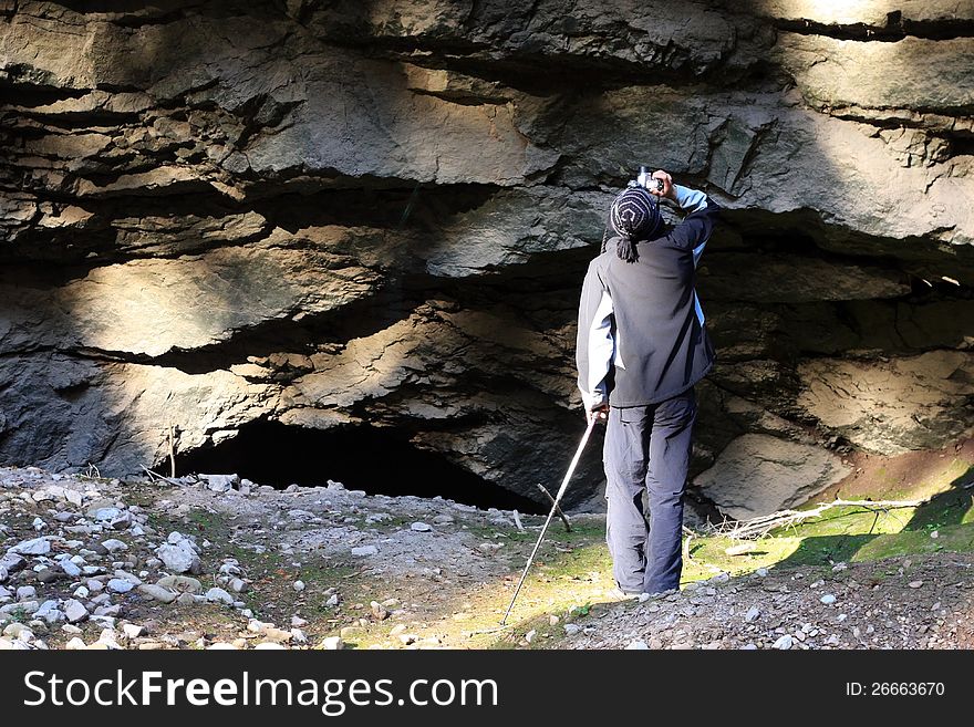 This image presents a wild life passionate photographer taking pictures in front of a big wall of rocks.