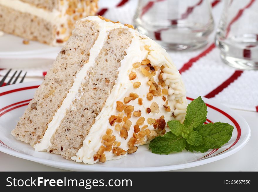 Slice of cake with white icing on a plate with mint leaves. Slice of cake with white icing on a plate with mint leaves