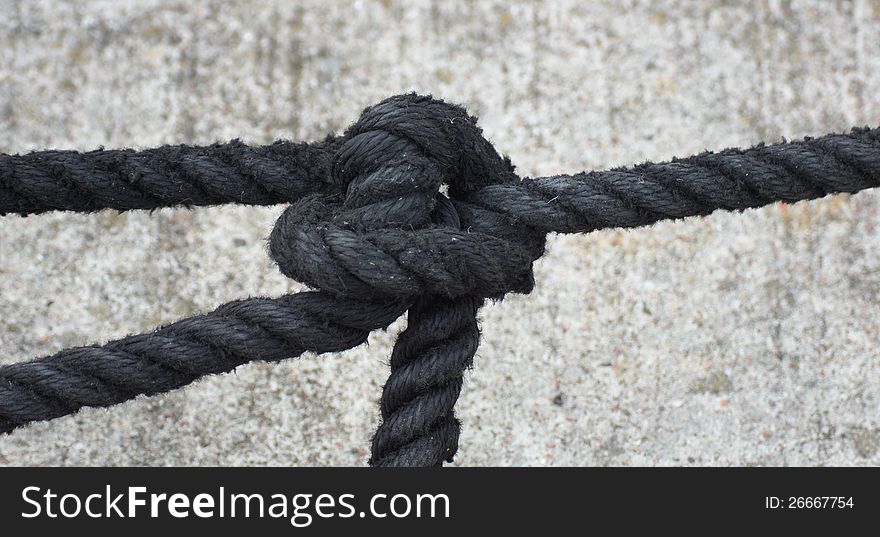 Black rope on gray background - knot. Black rope on gray background - knot