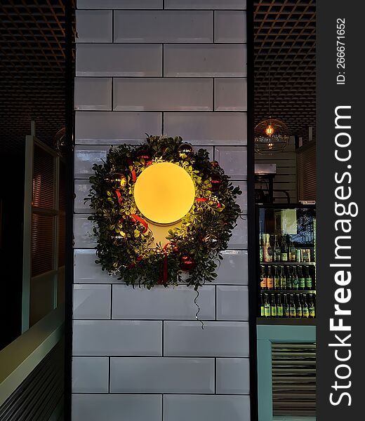 Yellow Lamp On A Brick White Wall With A Green Christmas Wreath