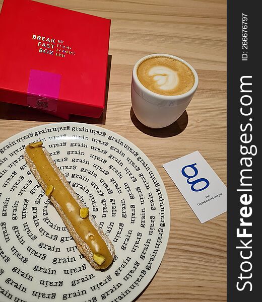 Pistachio Eclair On A Plate And A Cup Of Coffee