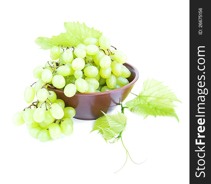 Bowl with grape cluster with leaves on a white background