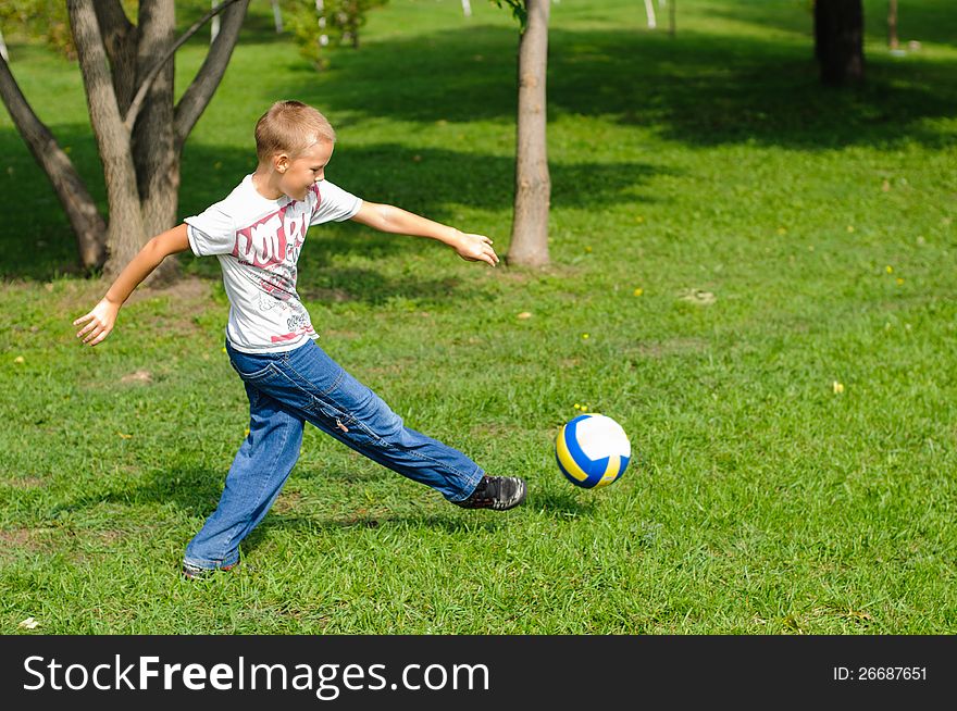 Young boy playing with his ball in the grass outdoors. Young boy playing with his ball in the grass outdoors