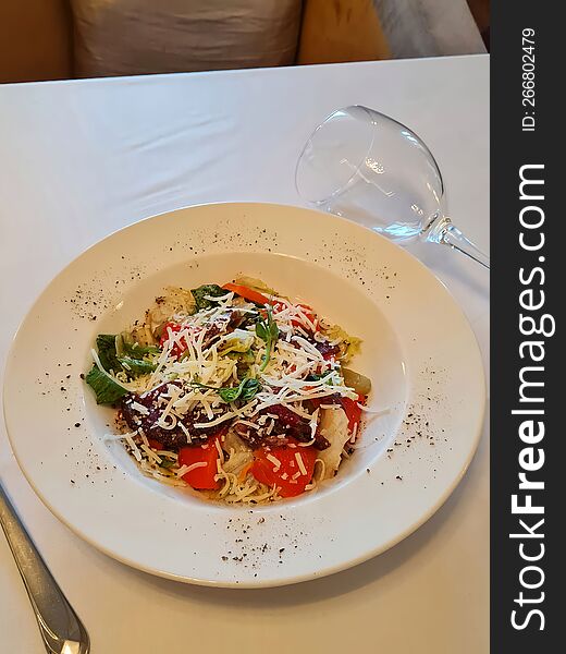 Salad With Cheese, Vegetables And A Glass Of Wine On A White Table