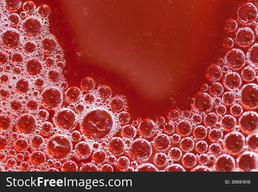 Closeup of bubbles in red juice drink.
