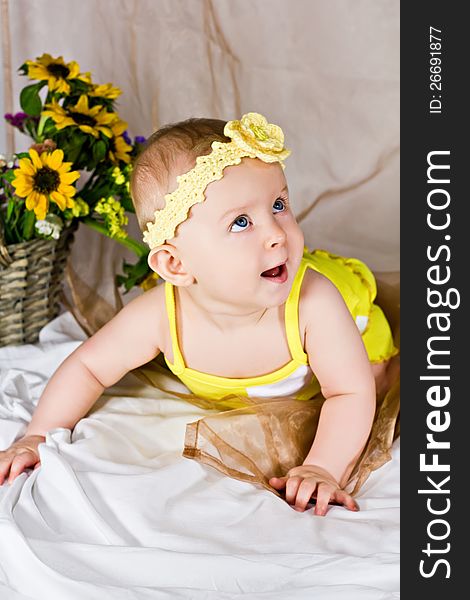 Beautiful baby girl with yellow flowers smiling and looking up. Beautiful baby girl with yellow flowers smiling and looking up