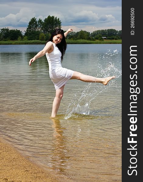 Happy young woman splashing water while having fun