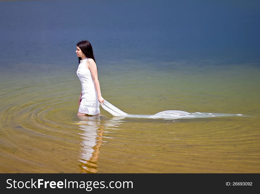 Woman in white dress in the water of the lake