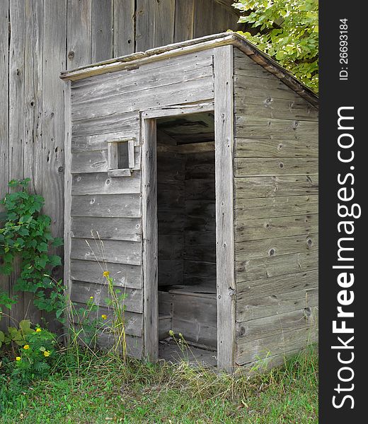 Old gray wooden outhouse.