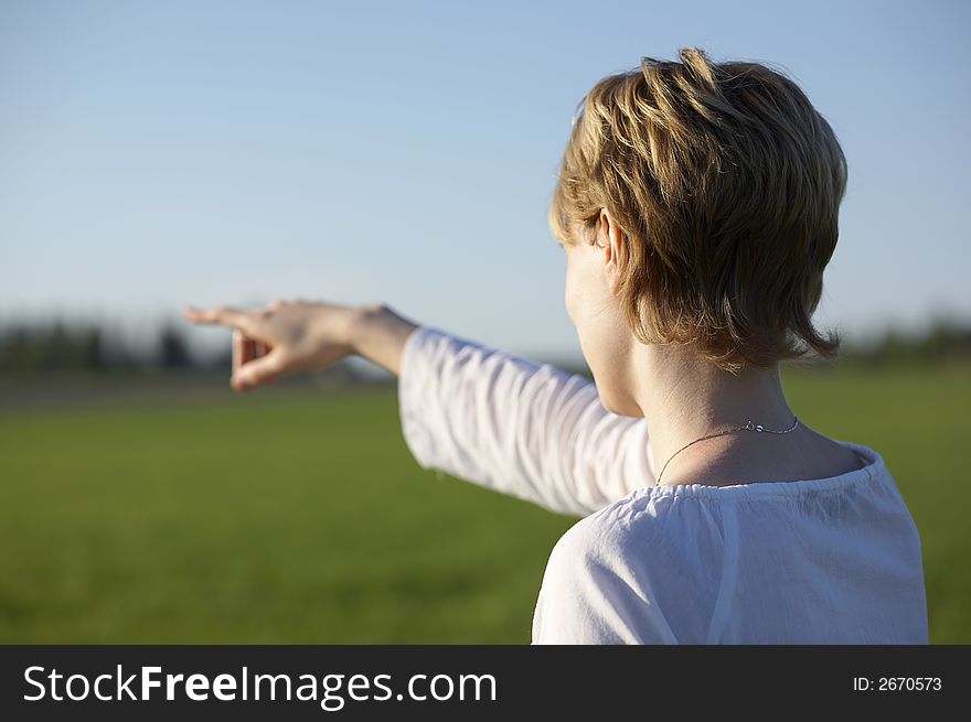 Young woman pointing something on the field. Young woman pointing something on the field