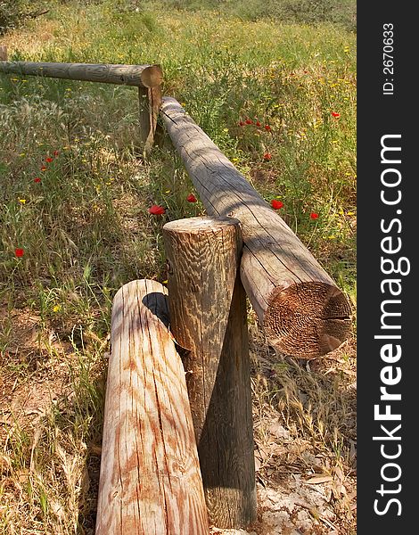 A small fence from logs on a blossoming meadow. A small fence from logs on a blossoming meadow