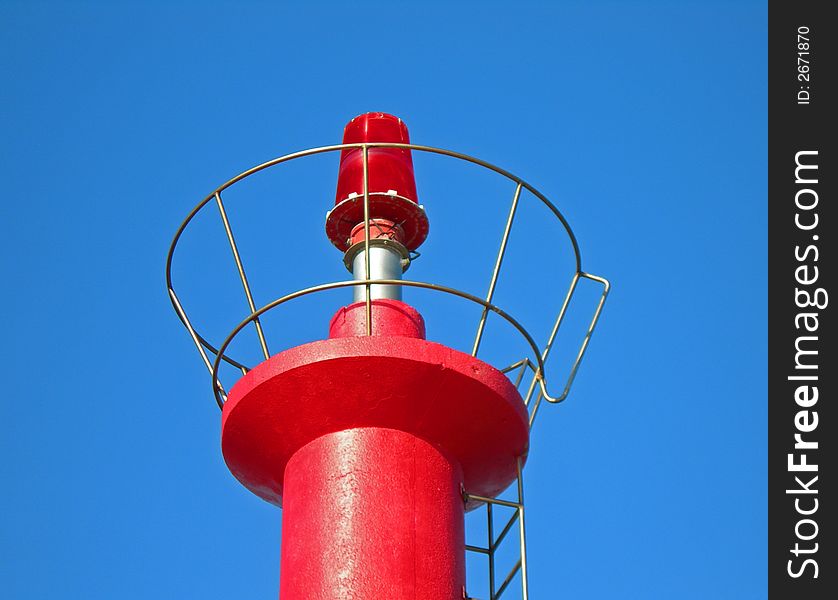 Brilliant red lighthouse against clear blue sky