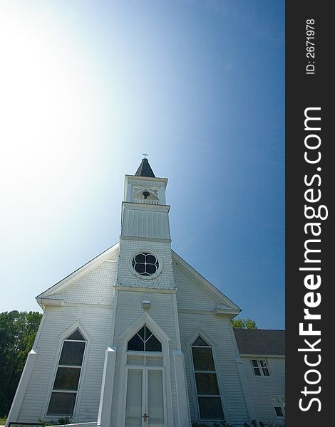 A white clapboard country church with a blue sky above. A white clapboard country church with a blue sky above