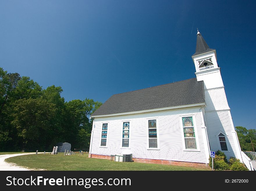 A white clapboard country church with a blue sky above. A white clapboard country church with a blue sky above