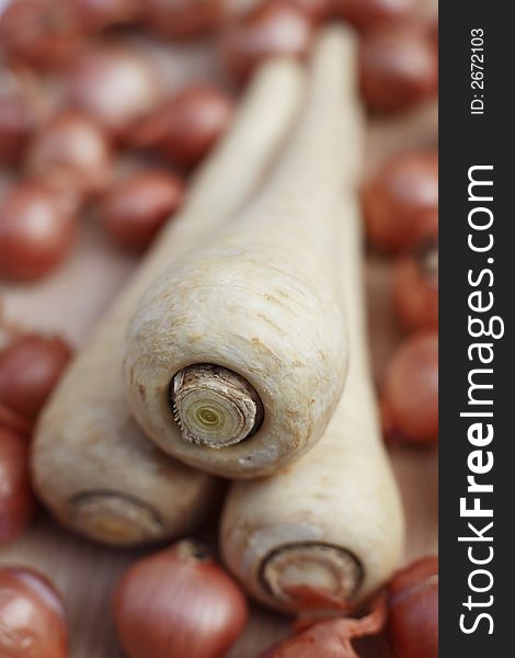 Fresh organic parsnips and shallots on chopping board