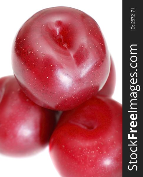 Close-up of stacked organic juicy plums on white background