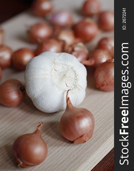 Fresh shallots and whole garlic on chopping board. Fresh shallots and whole garlic on chopping board