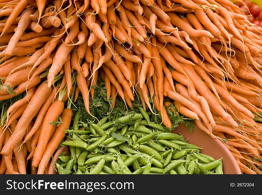 Big pile of bright colored carrots and snap peas at Farmers Market