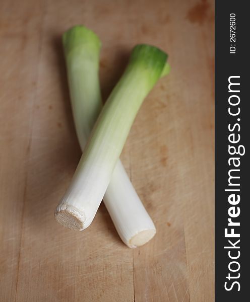 Uncooked fresh leeks on chopping board