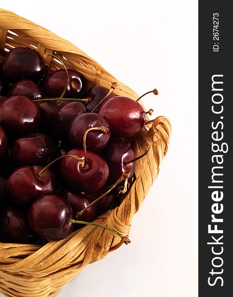 A handmade basket with delicious red ripe cherries, isolated in a white background in studio conditions. A handmade basket with delicious red ripe cherries, isolated in a white background in studio conditions.